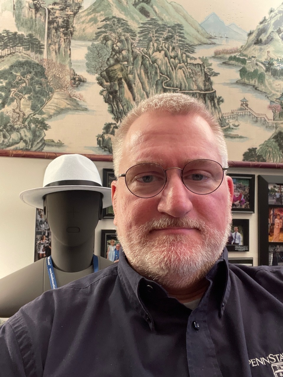 photograph of Dr.Dan Russell in his office with binaural head in the background. Photo taken in 2023.